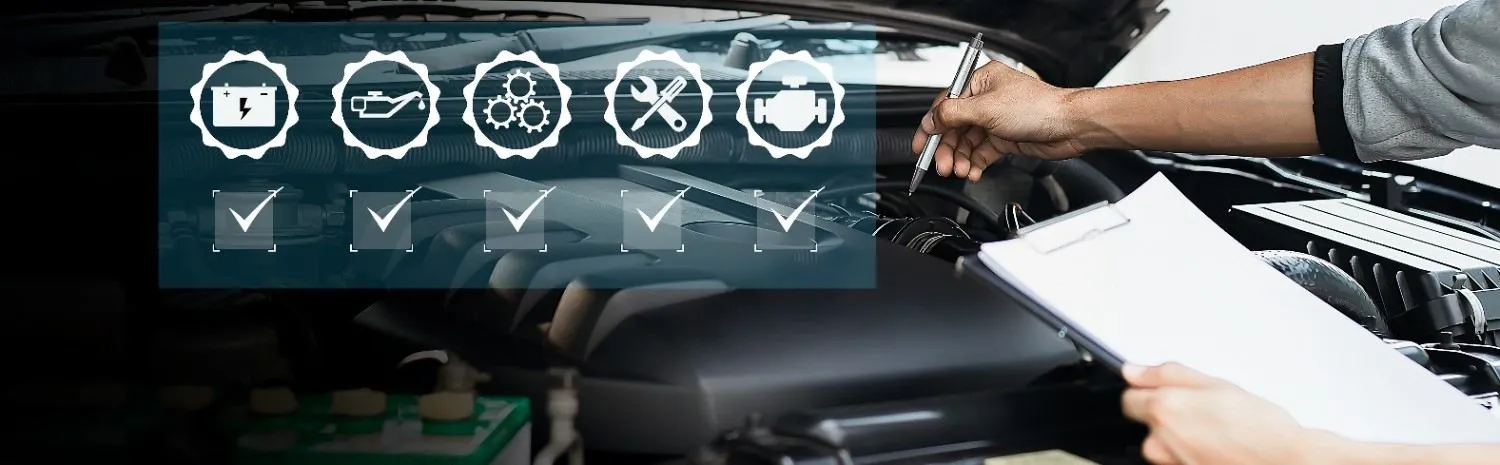 Mechanic checking items off a list on a clipboard beside an open engine bay